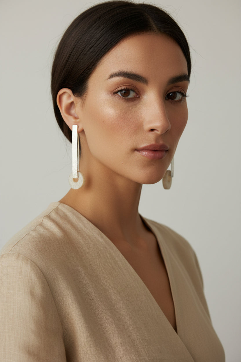 Woman wearing silver horn bar drop earrings, minimalist portrait, neutral tones