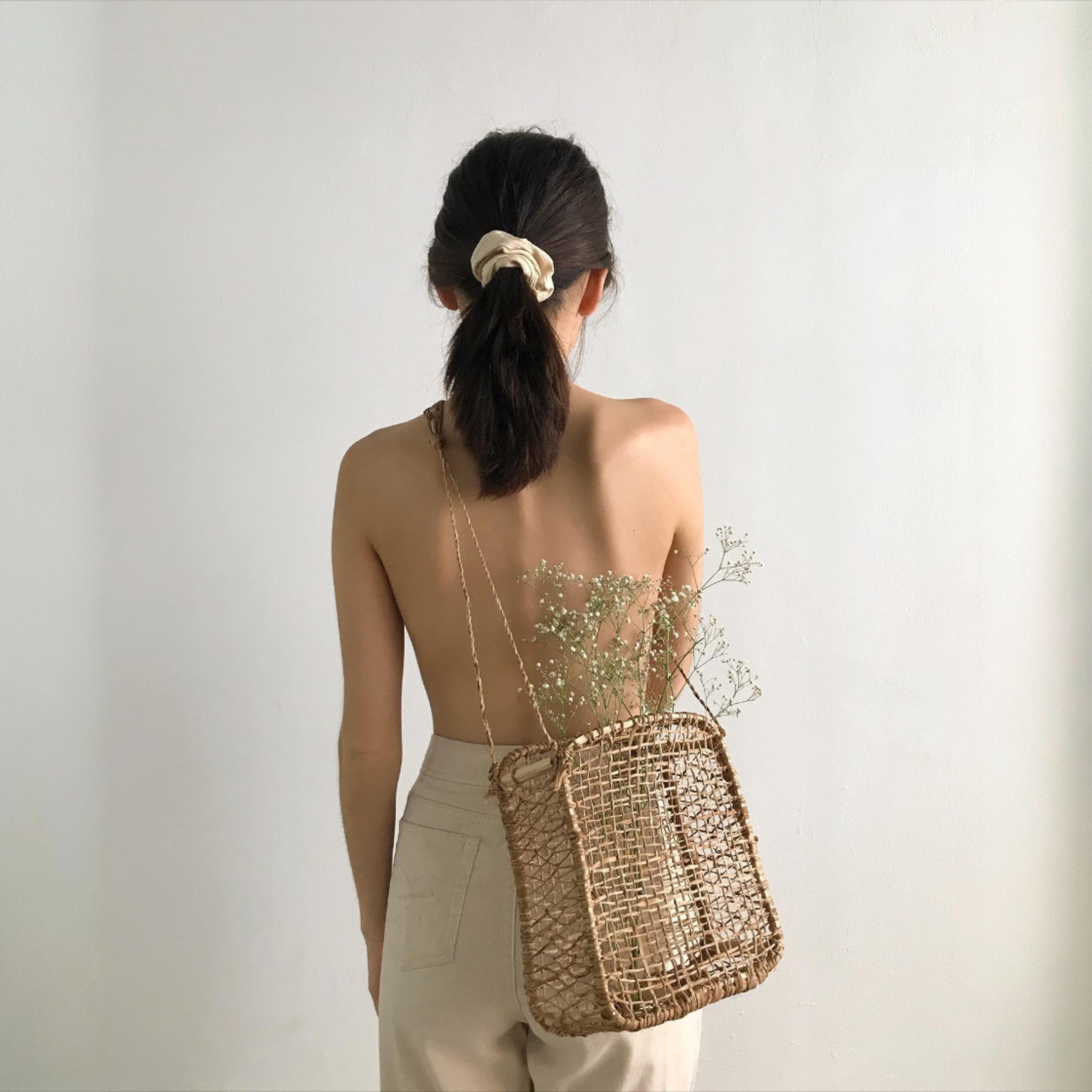 Handwoven square jonote basket worn as a crossbody bag, minimal white backdrop