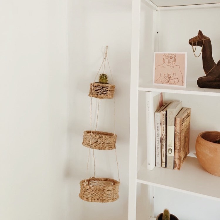 Three-tier circular jonote hanging basket displayed next to a bookshelf.