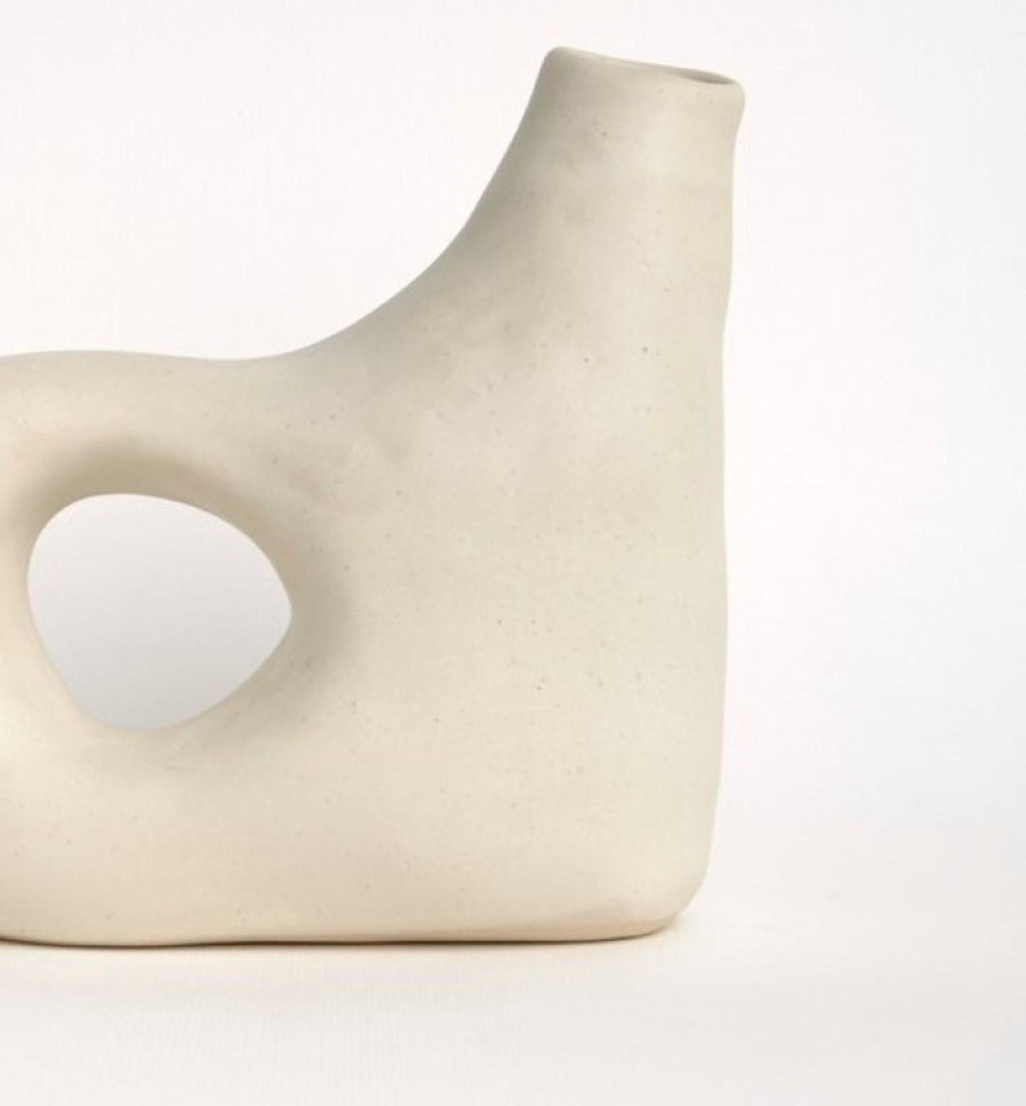 Close-up of curved spout ceramic vase highlighting its smooth matte texture and circular opening.