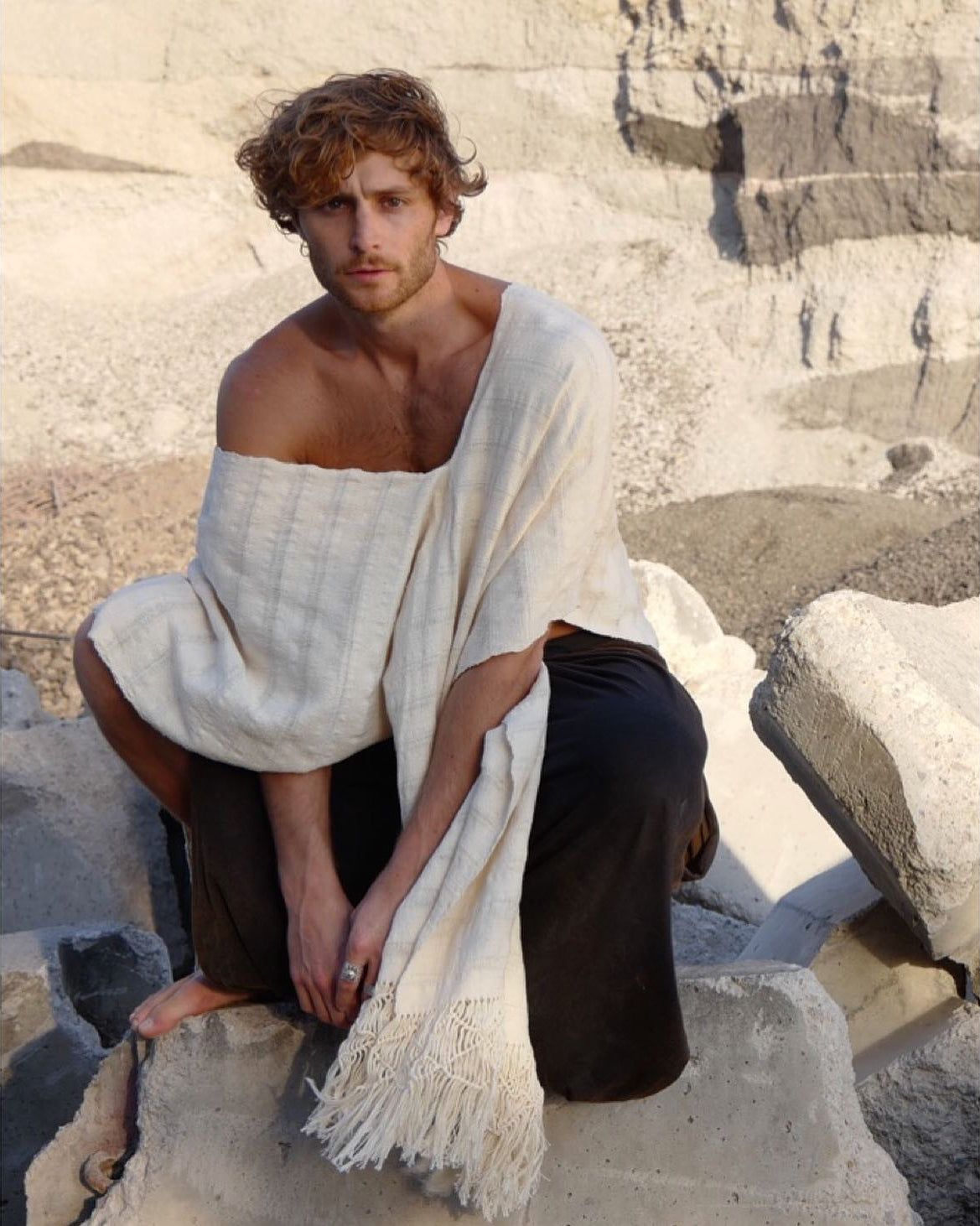 Model wearing a handwoven cotton poncho dress styled casually outdoors on stone steps
