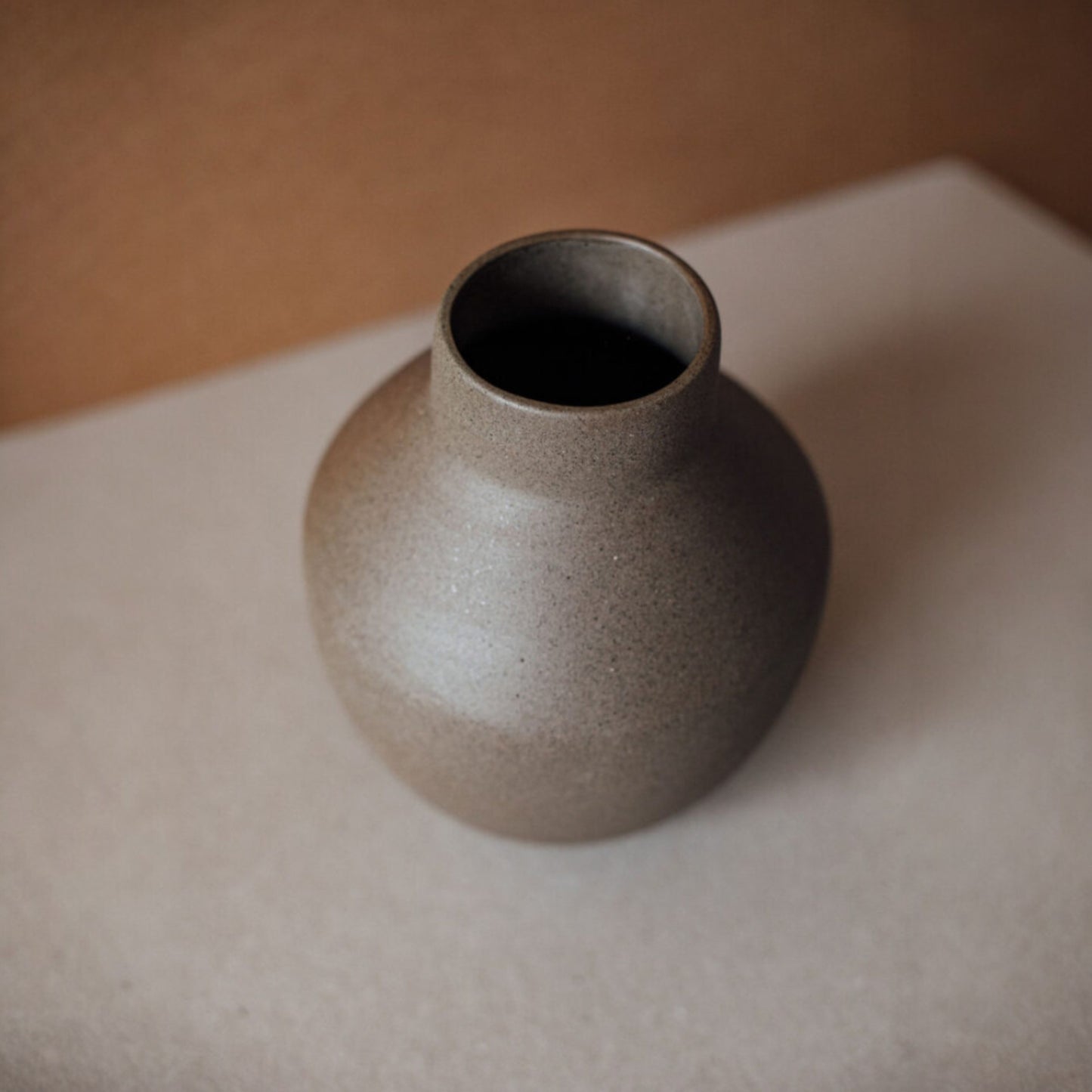 Top view of handmade round ceramic vase with narrow opening and natural clay color.