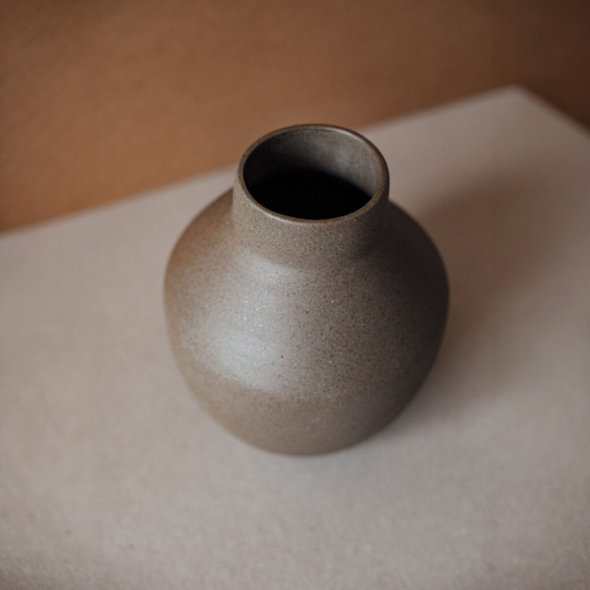 Top view of handmade round ceramic vase with narrow opening and natural clay color.