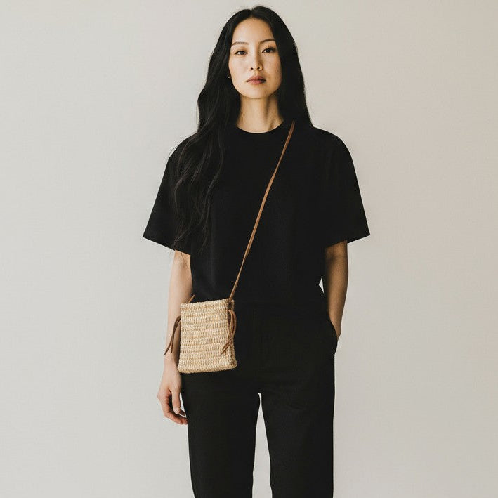 Front view of a woman wearing a handmade agave fiber crossbody bag on a neutral background