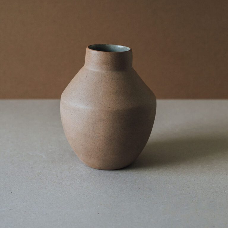 Handcrafted round terracotta vase showing natural two-tone clay texture.