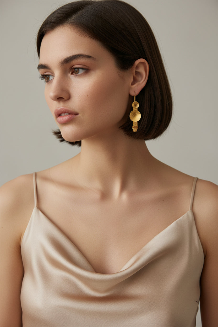 Model wearing gold plated hammered disc dangle earrings, minimalist sculptural jewelry