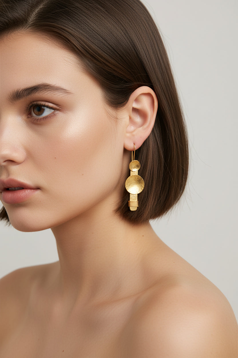 Model wearing gold plated disc earrings, elegant studio portrait