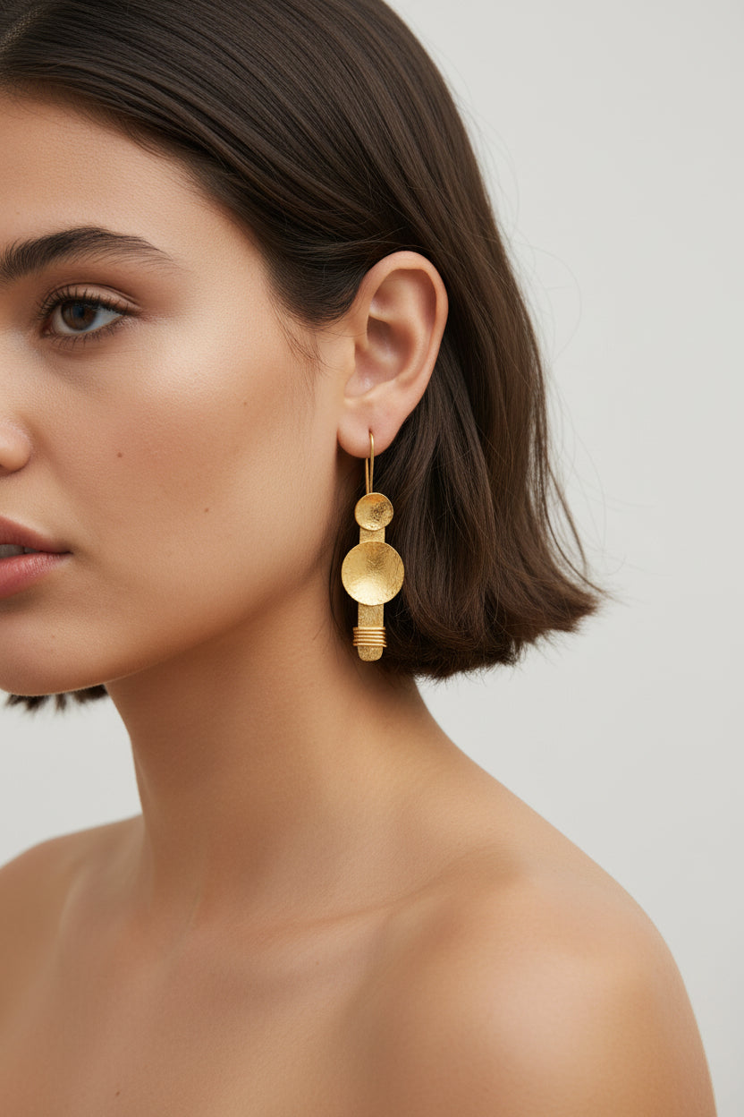 Model wearing gold plated disc dangle earrings, clean studio portrait