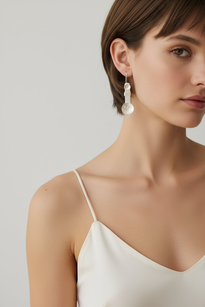 Model wearing silver plated disc dangle earrings, clean studio portrait