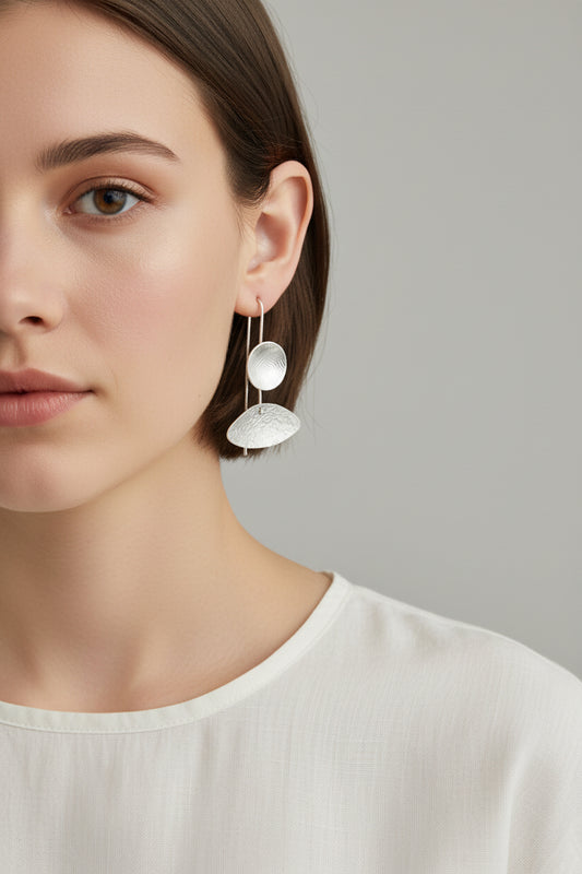 Woman wearing asymmetrical silver sculptural drop earrings