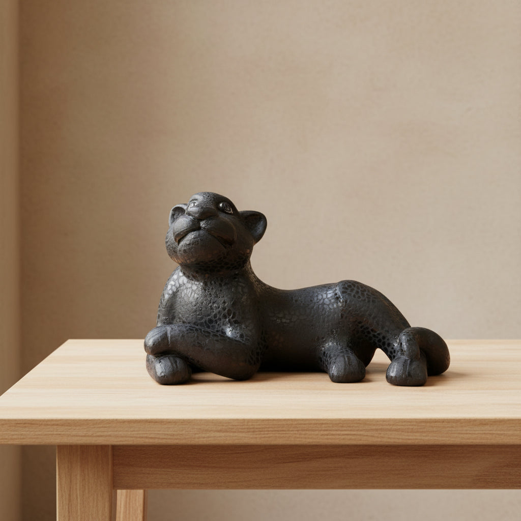 Black Mayan jaguar pottery sculpture displayed on light wood table, close-up view
