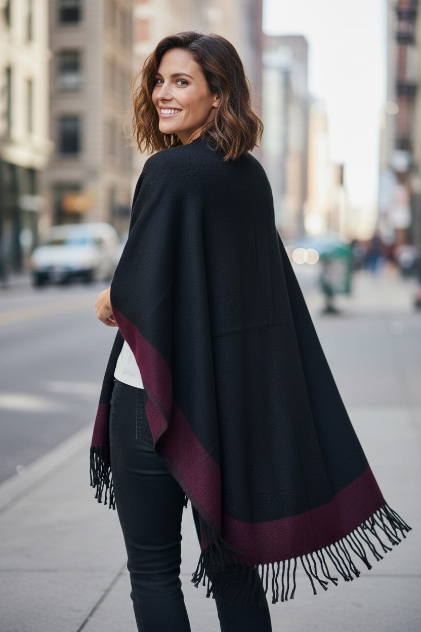 Back view of the reversible black and burgundy wool blend ruana wrap with fringe, showing the black side as the primary color.