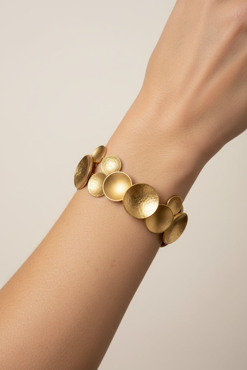Close-up of gold Cascade Disc Cuff bracelet on wrist, hammered disc texture detail