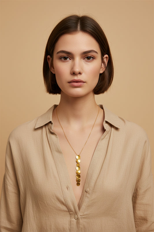 Woman wearing gold cascade disc pendant necklace, close-up