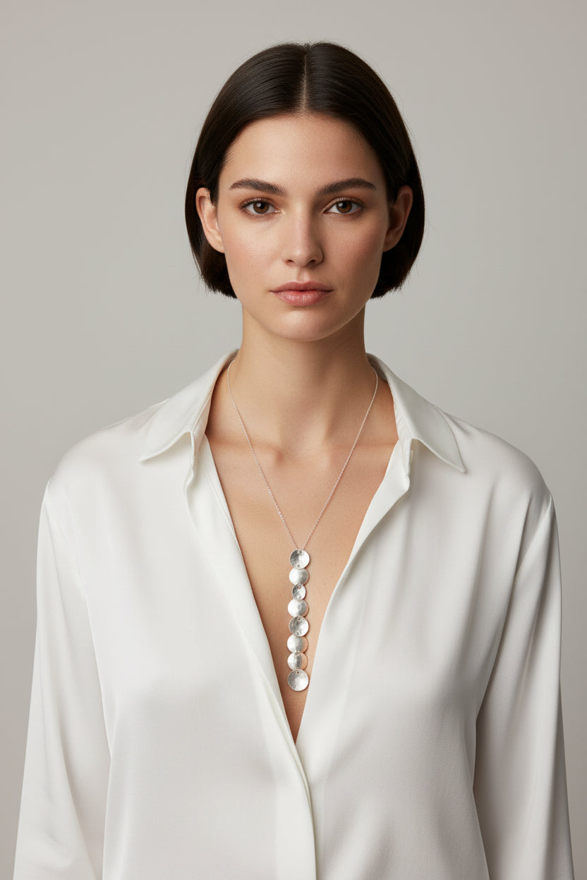 Woman wearing silver cascade disc pendant necklace with white blouse