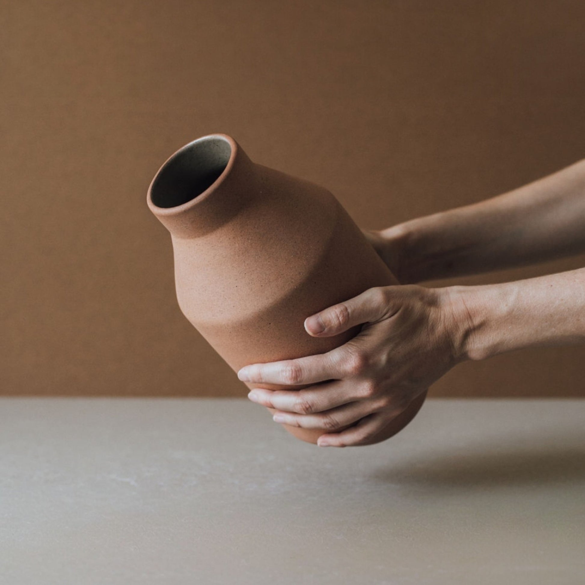 Handmade chocolate terracotta vase held in hands showing size and earthy texture