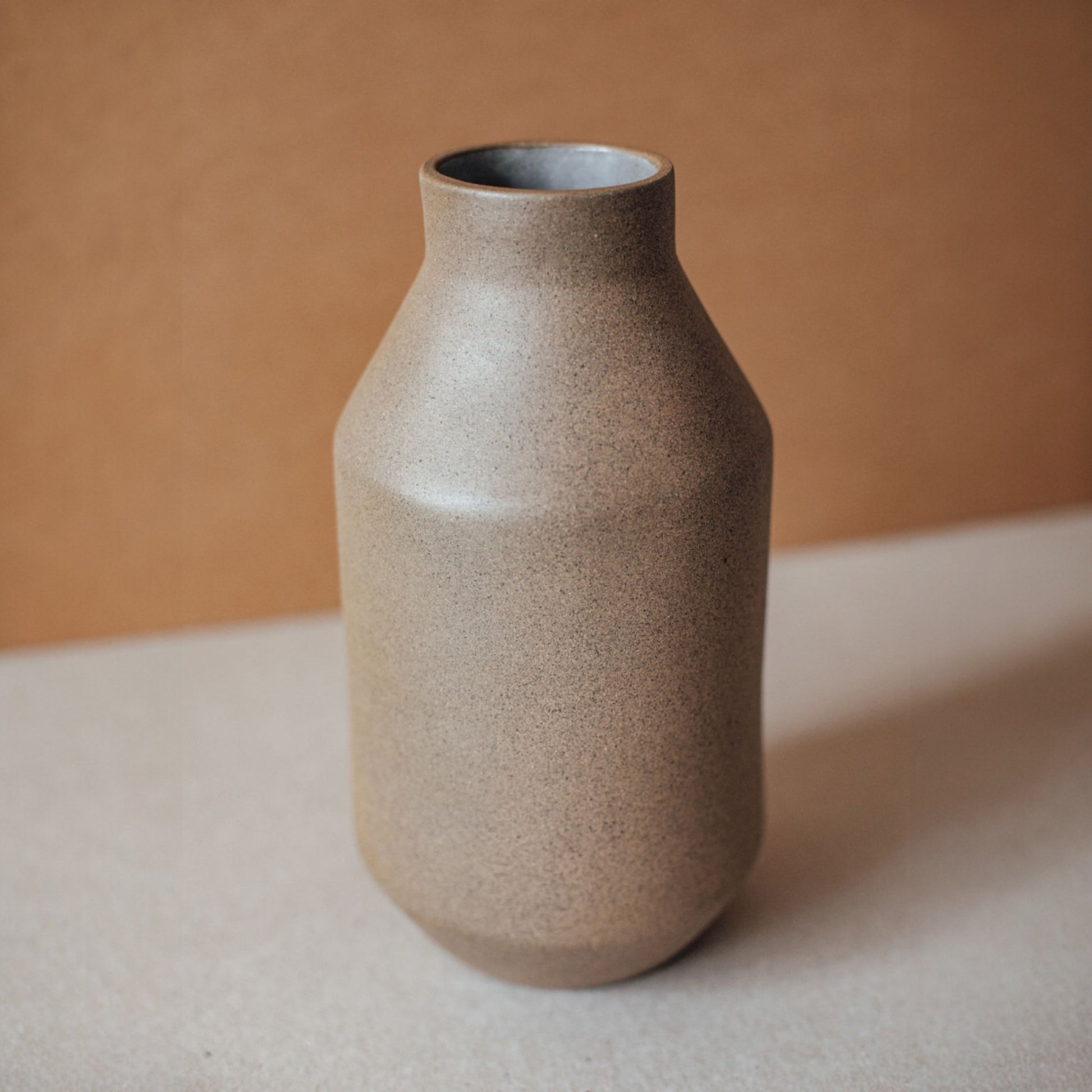 Matte sand ceramic vase with minimalist Japandi form styled on light surface