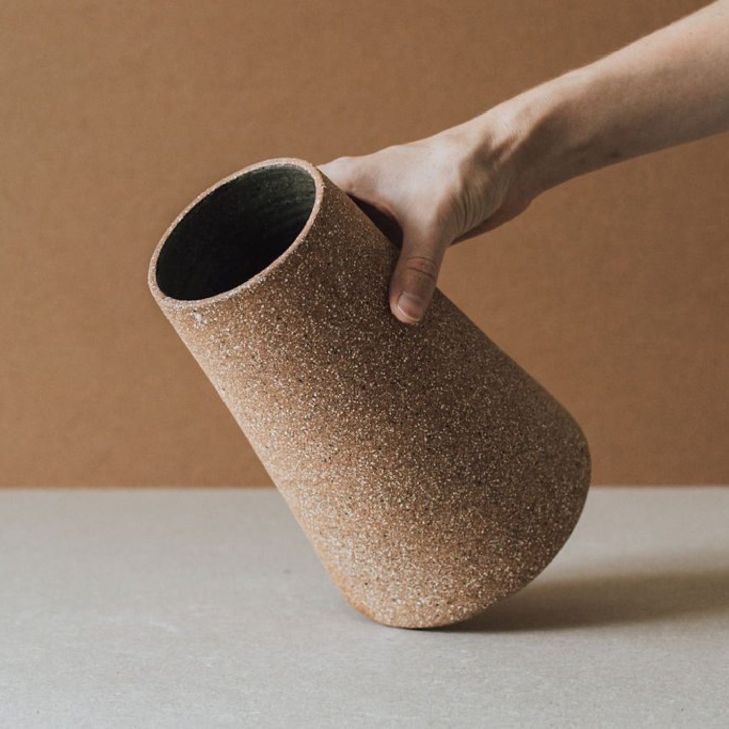 Handmade terracotta cone vase showing textured sand clay surface and transparent glazed interior