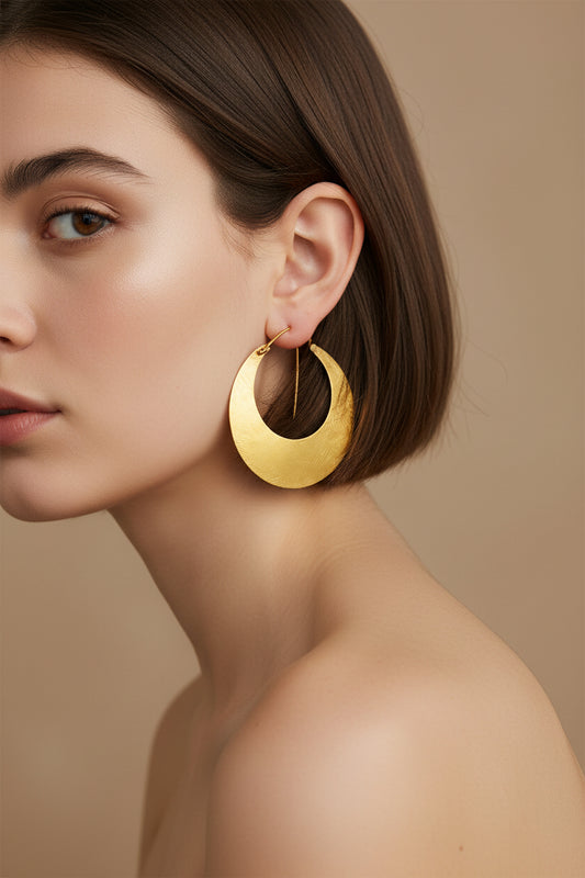 Model wearing gold crescent moon hoop earrings, close-up side profile