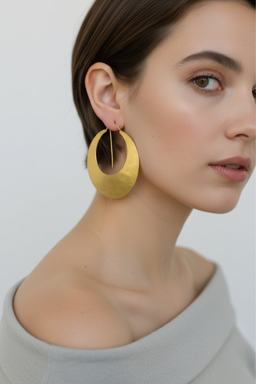 Model wearing gold crescent moon hoop earrings, close-up portrait