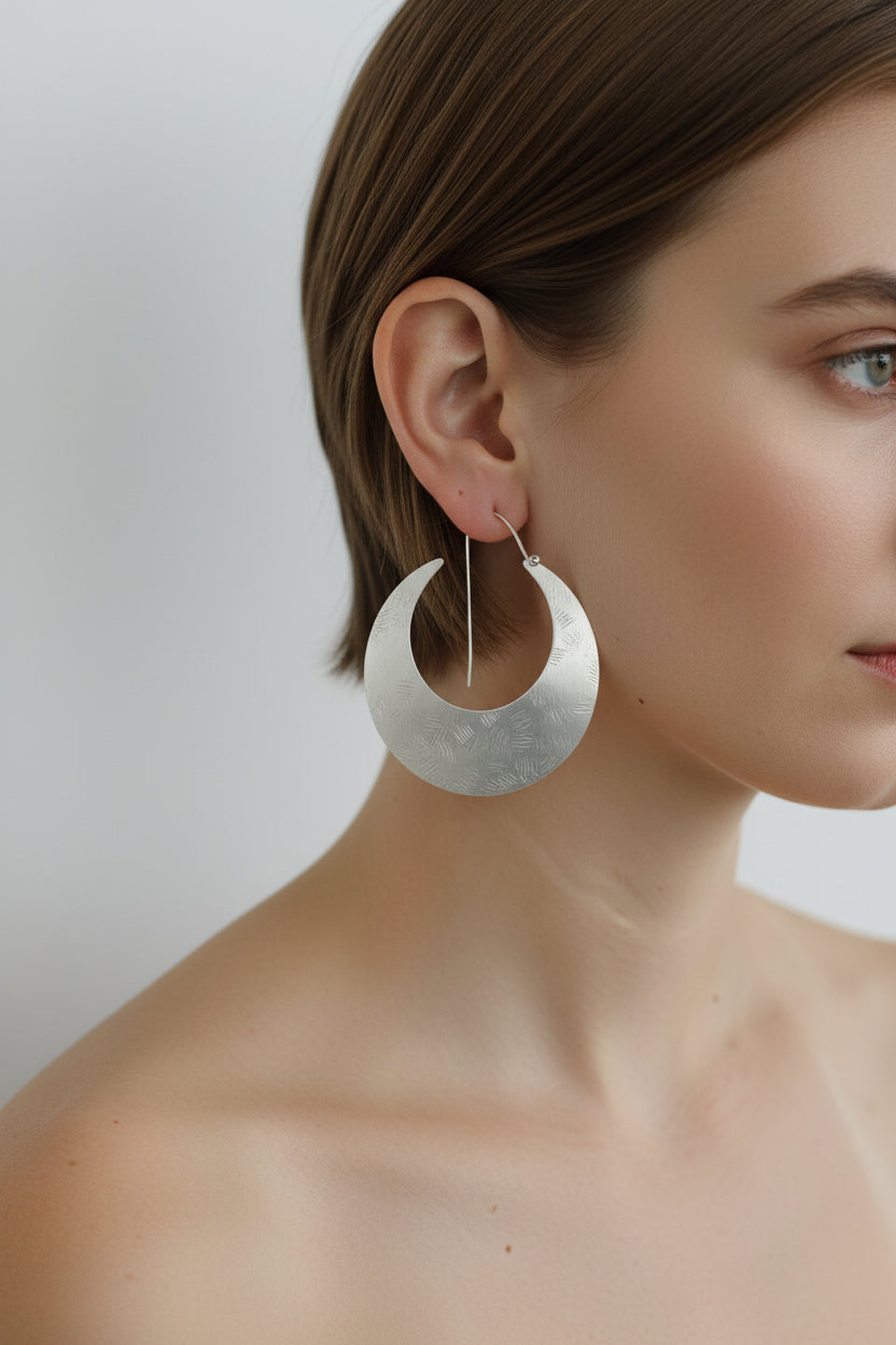 Model wearing silver crescent moon hoop earrings, close-up side view
