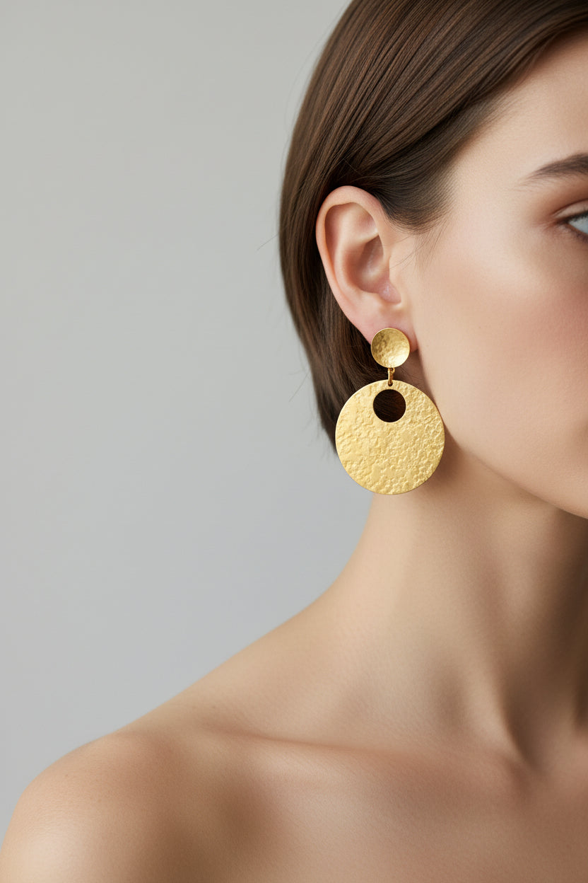 Model wearing gold hammered circular earrings, side view
