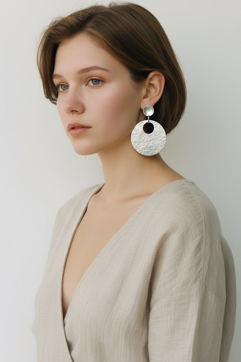 Model wearing silver hammered circular earrings, front view