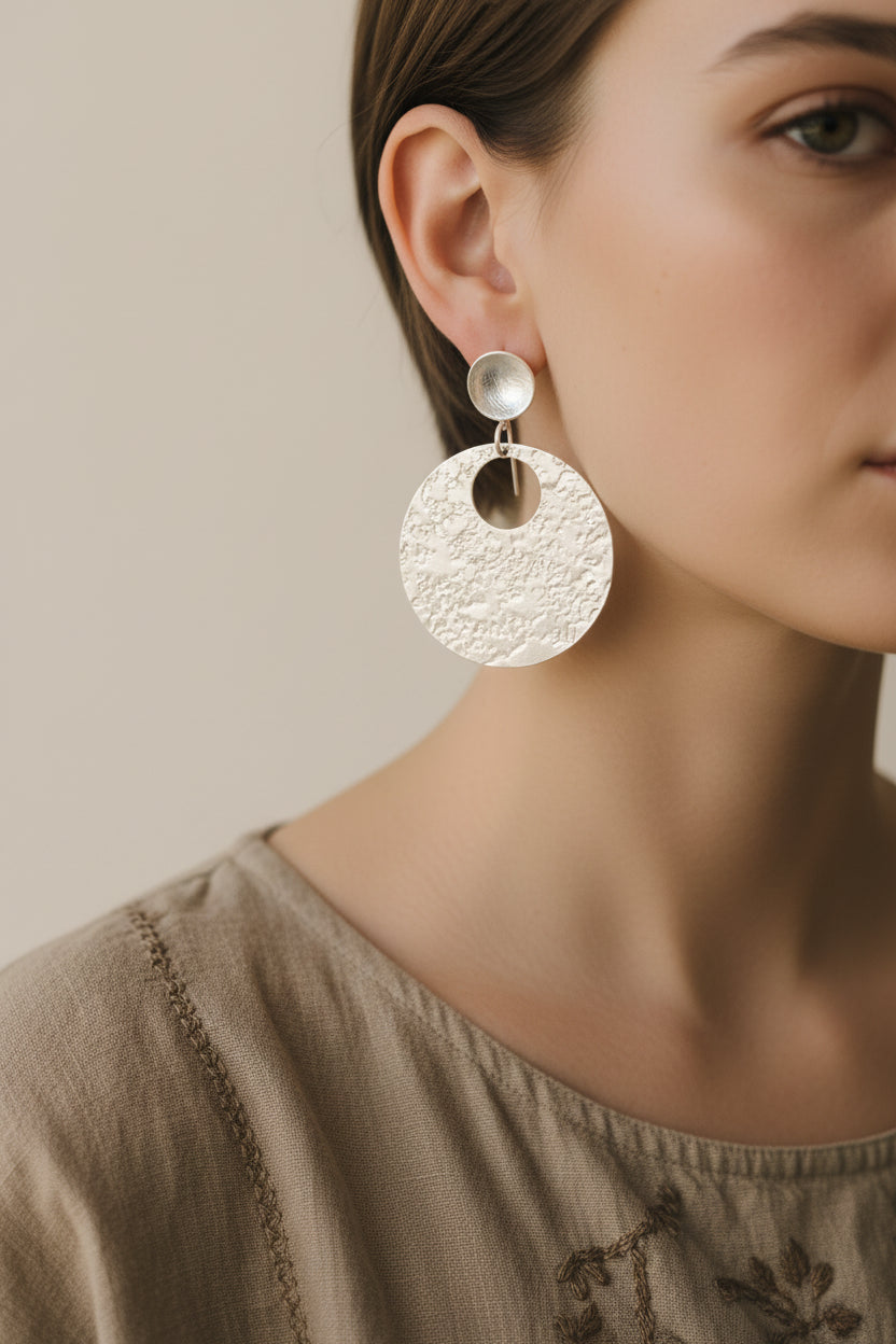 Model wearing silver hammered circular earrings, close up