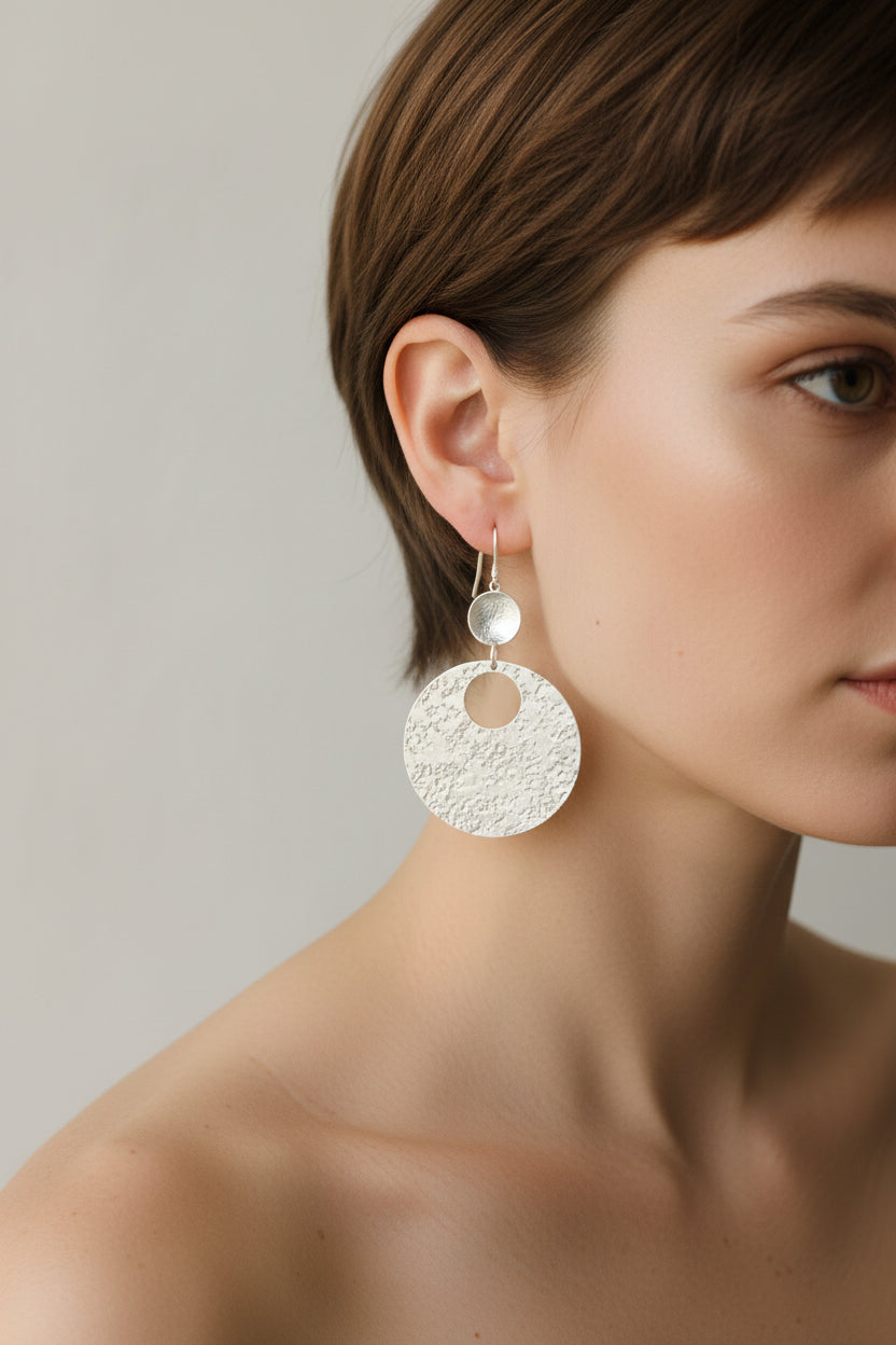 Model wearing gold hammered circular earrings, close up