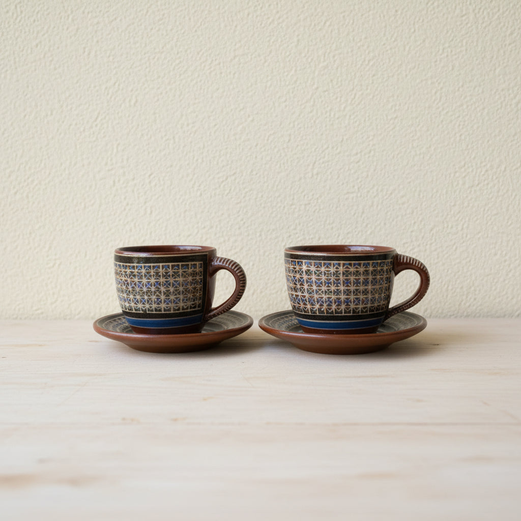 Set of two hand-painted Tonalá ceramic cups with matching saucers on natural surface
