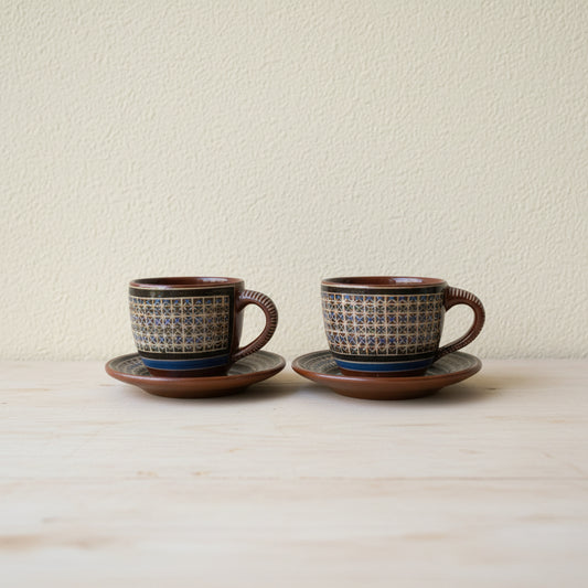 Set of two hand-painted Tonalá ceramic cups with matching saucers on natural surface