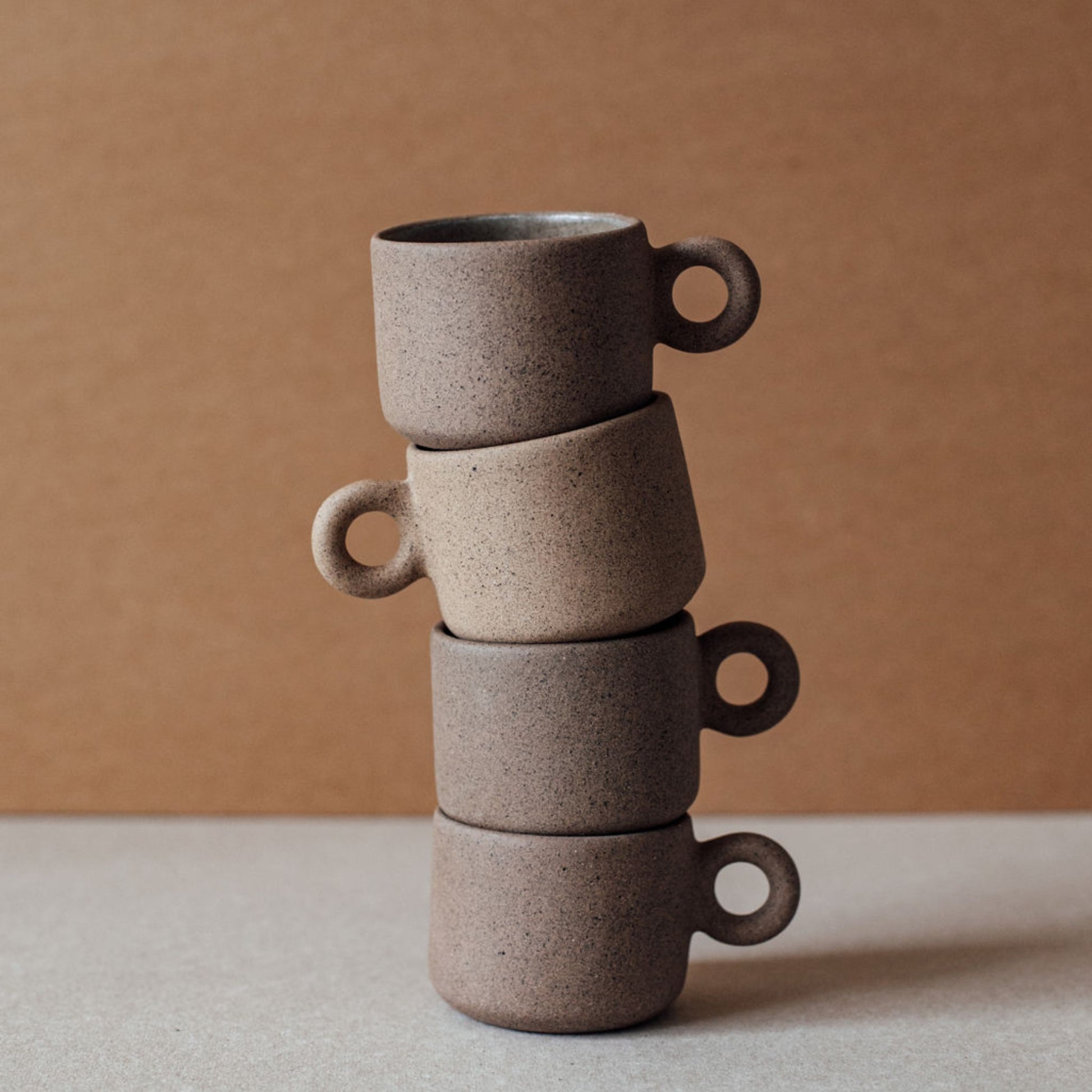 Stack of four terracotta ring cups with circular handles, sculptural minimalist ceramic drinkware