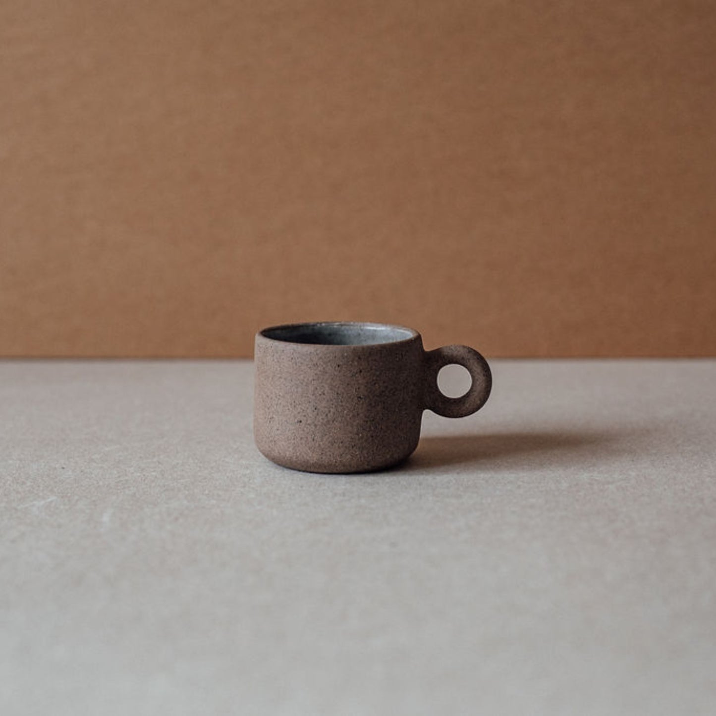 Single small ceramic ring cup in chocolate terracotta, modern rustic drinkware