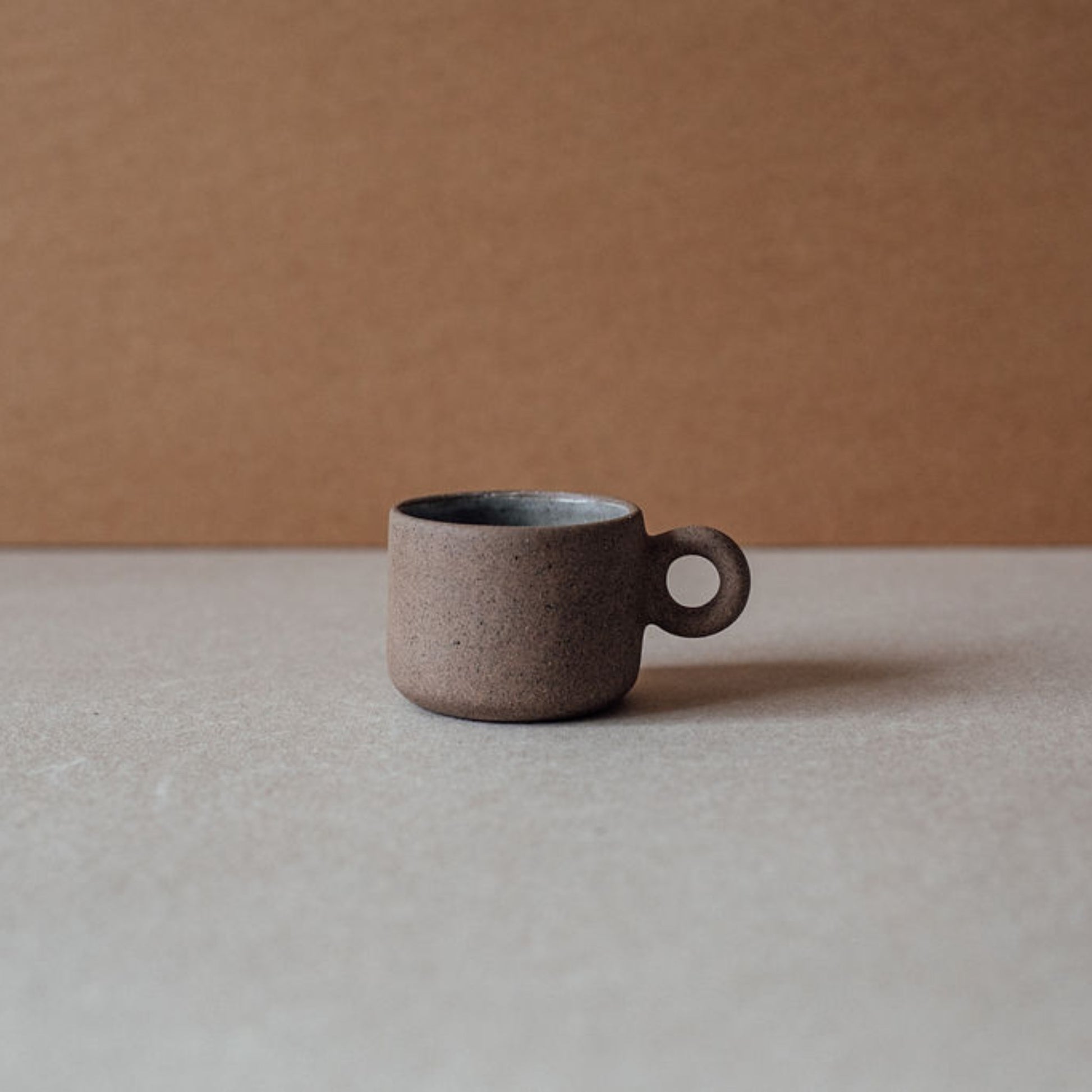 Single small ceramic ring cup in chocolate terracotta, modern rustic drinkware