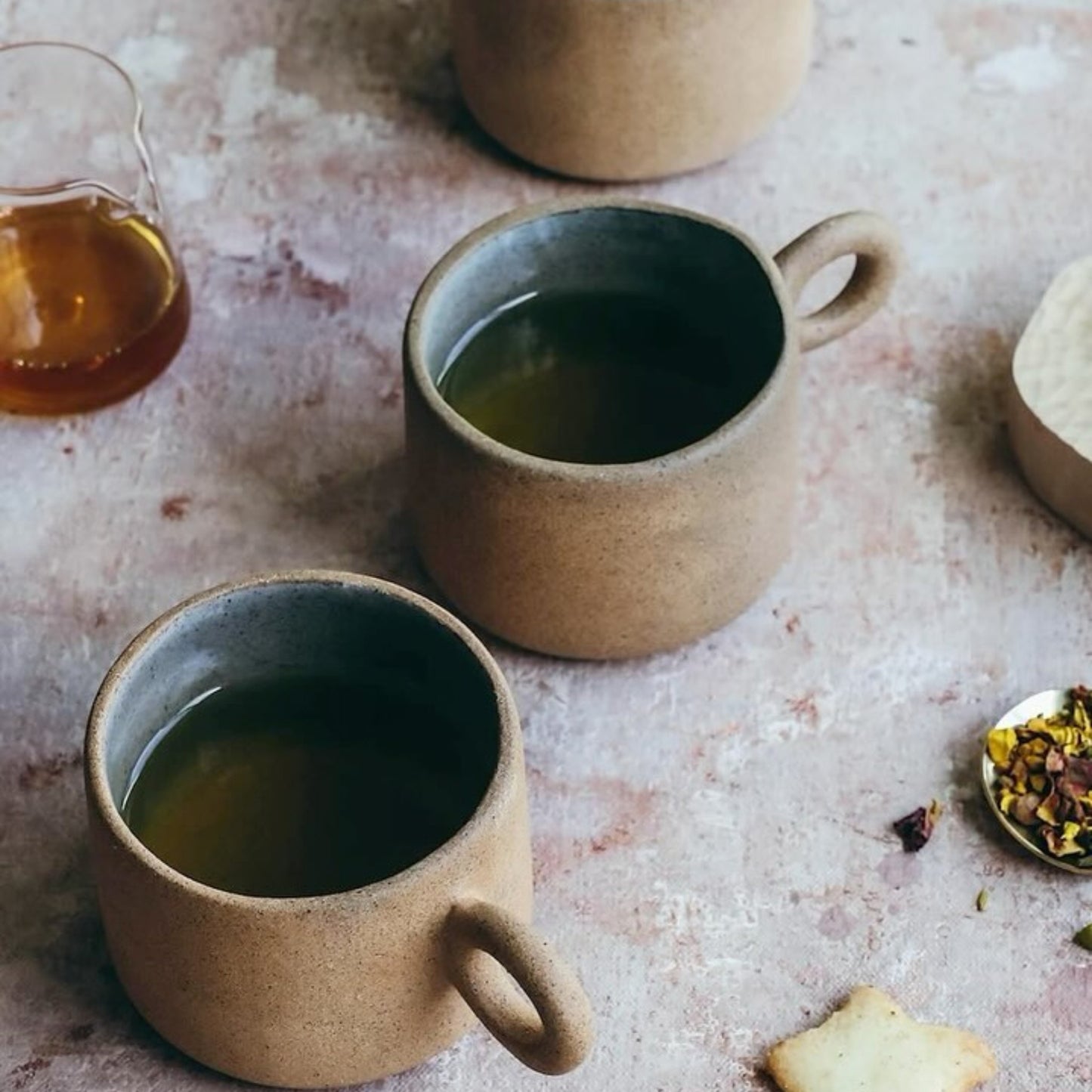 Top view of two terracotta ceramic cups filled with tea on textured table surface