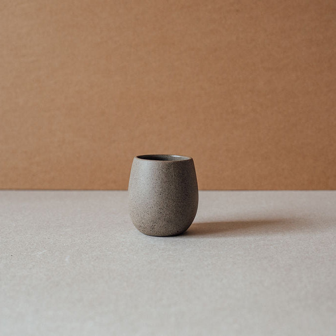 Single chocolate-tone ceramic cup on a neutral background.