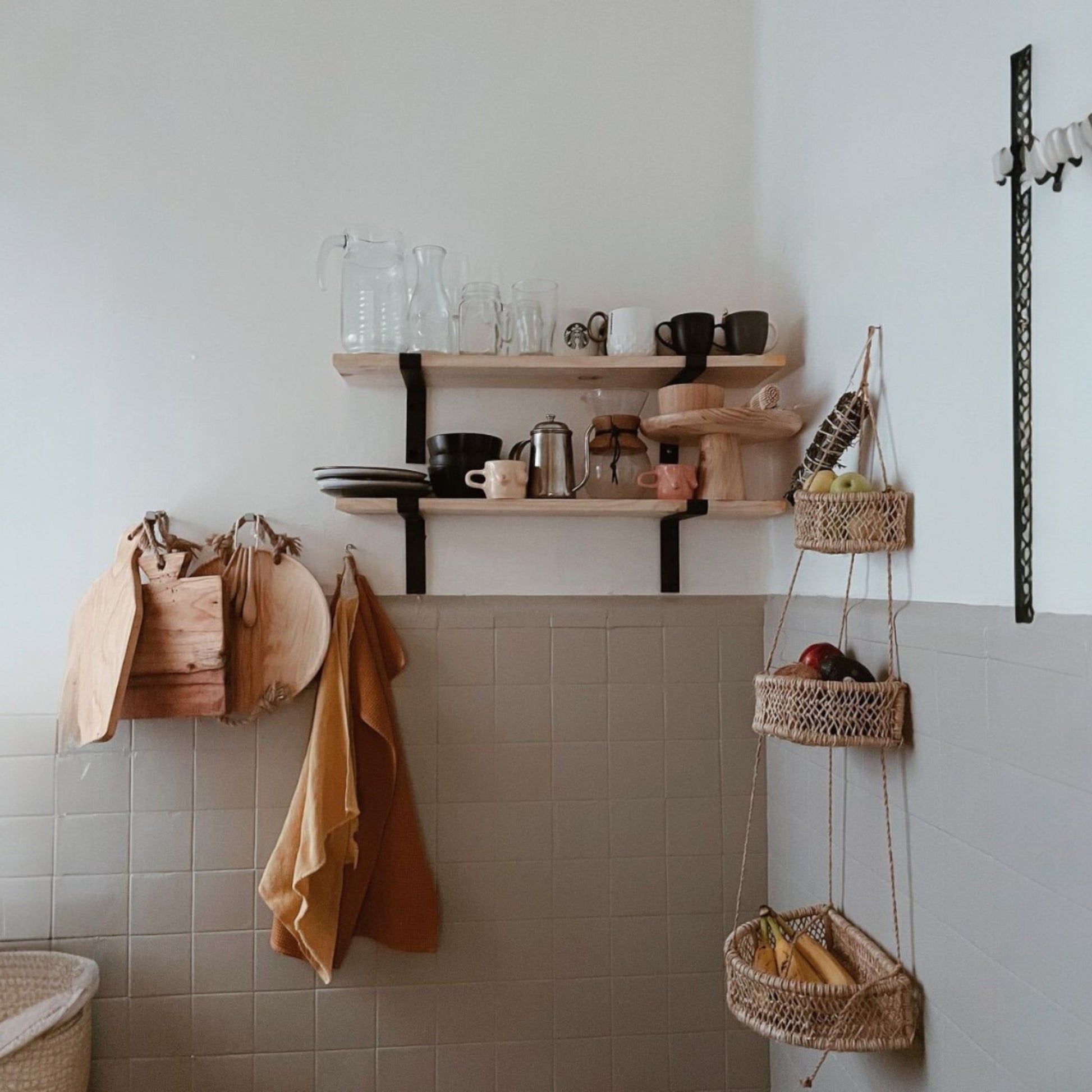 Kitchen corner with shelves and a three-tier woven hanging basket filled with fruits
