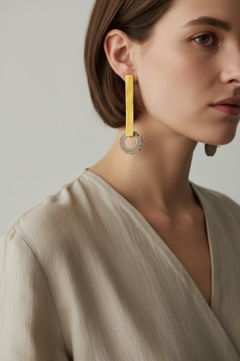 Woman wearing gold horn bar drop earrings, minimalist styling, close-up