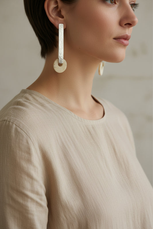 Woman wearing silver horn bar drop earrings, natural lighting, side profile