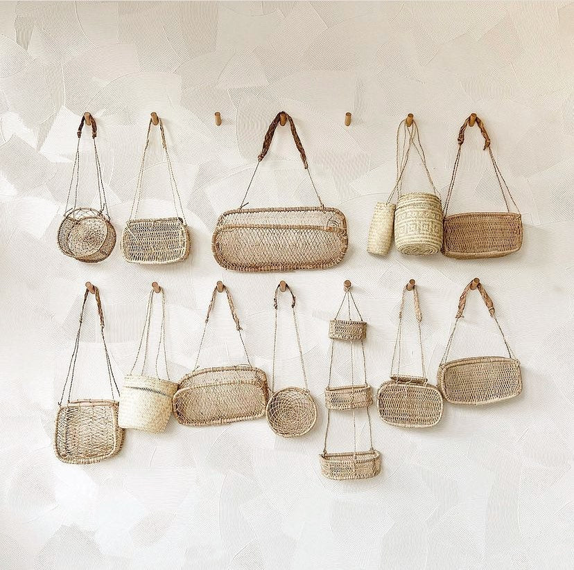 Assorted handwoven jonote hanging baskets displayed on a textured neutral wall.