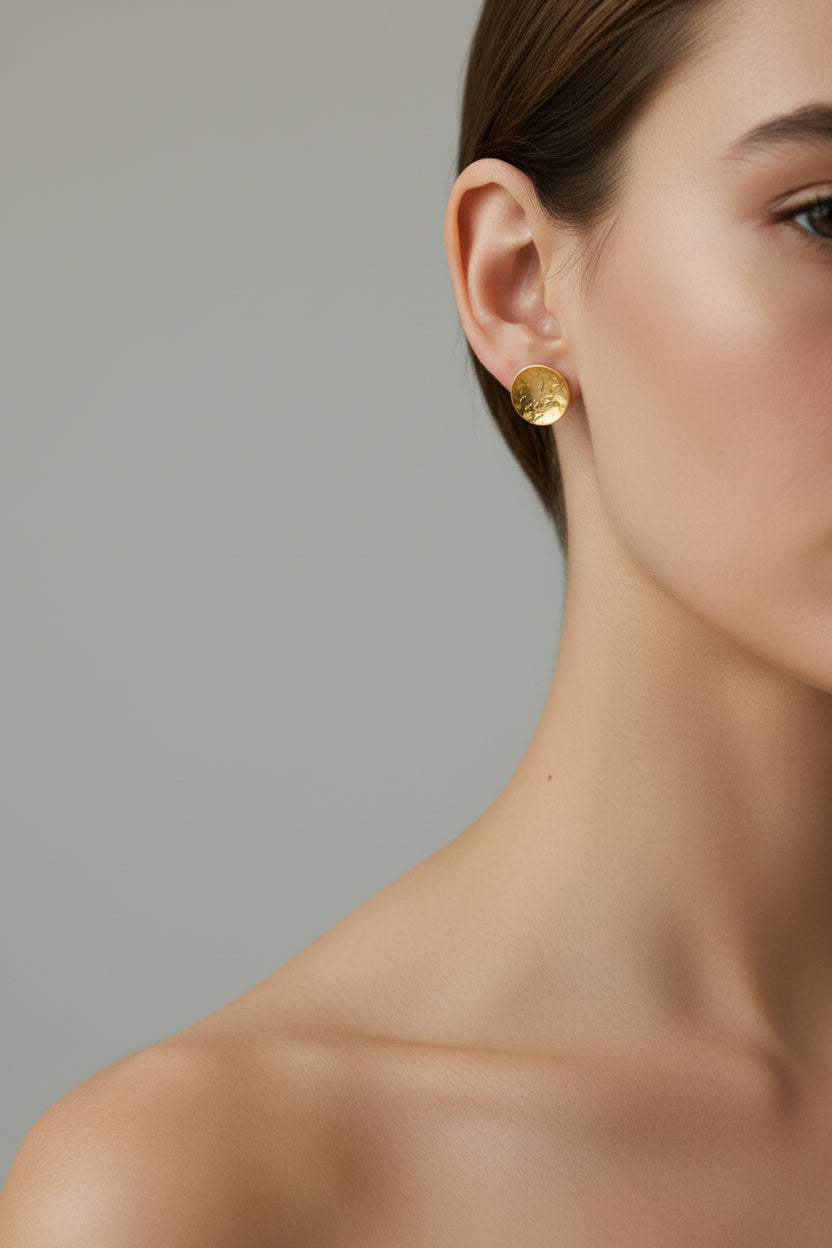 Handmade gold dome stud earrings worn by a woman against a neutral background
