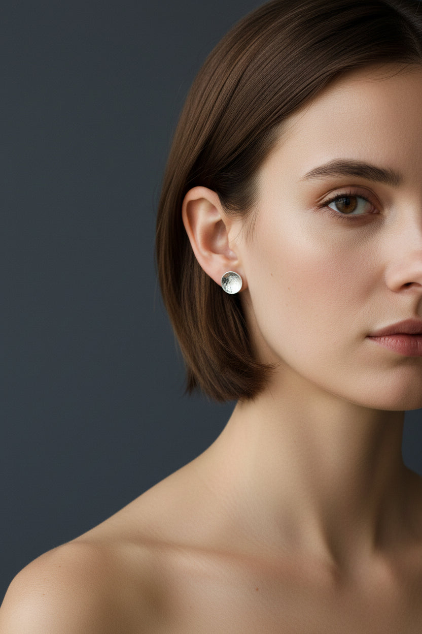 Handmade silver dome stud earrings worn by a woman against a neutral background
