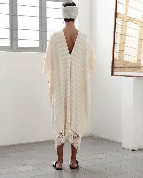 Back view of a handwoven cotton poncho dress showing open sides and V-back neckline