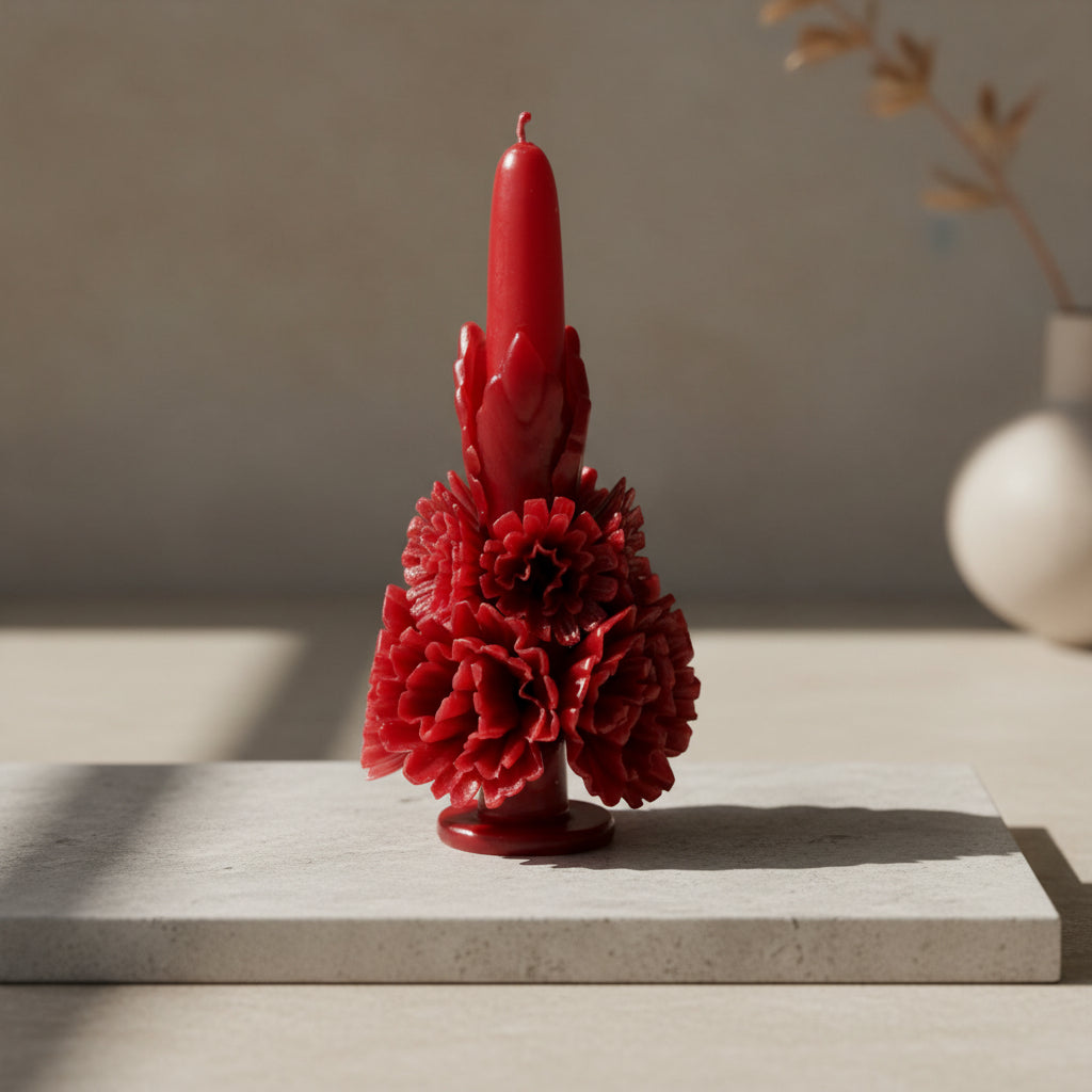Red carved beeswax floral candle styled on a stone surface