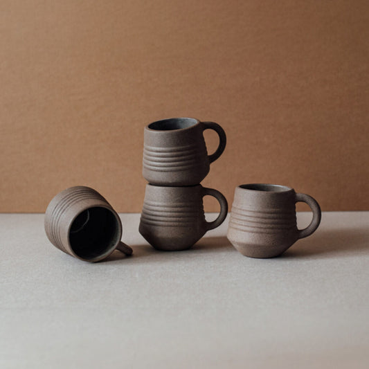 Ridge terracotta coffee mug set stacked with matching ceramic cups in earthy brown tones on neutral background