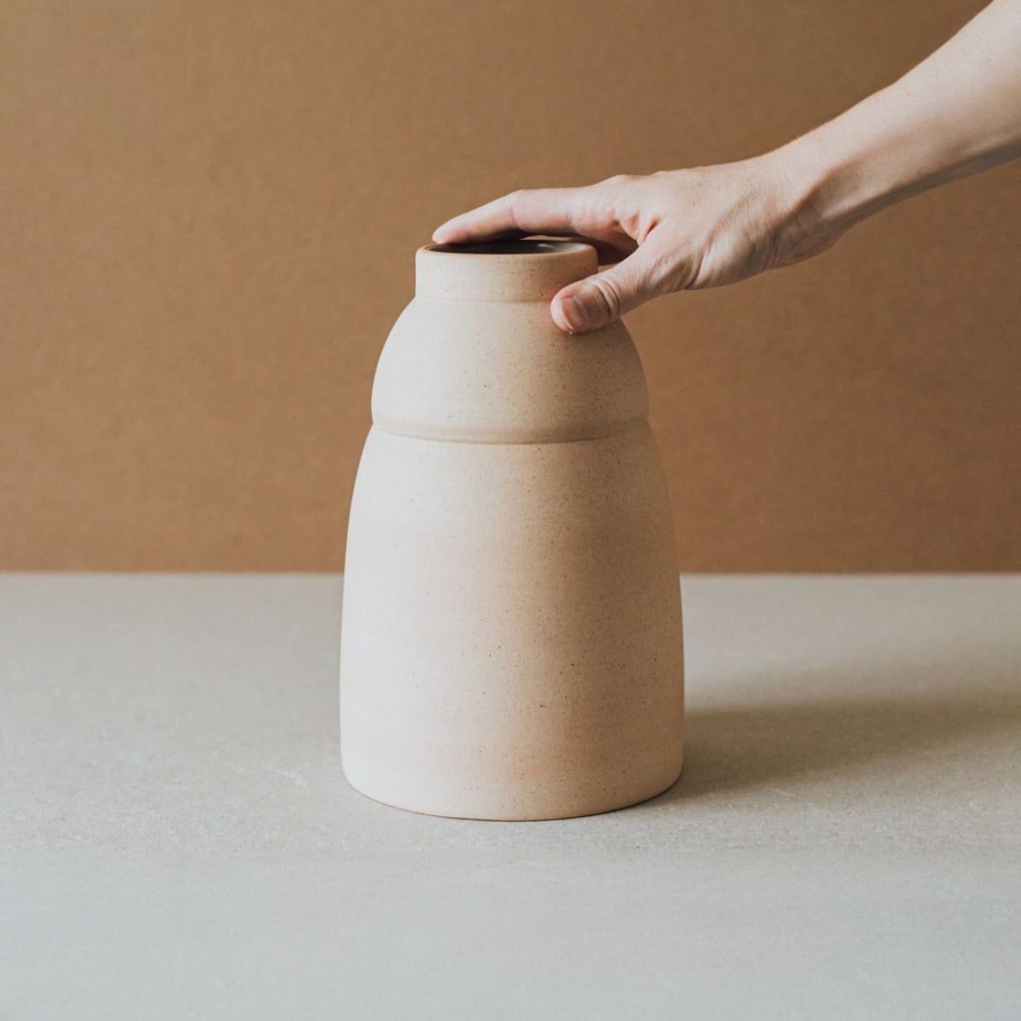 Artisan holding rounded terracotta ceramic vase showing scale and handmade craftsmanship