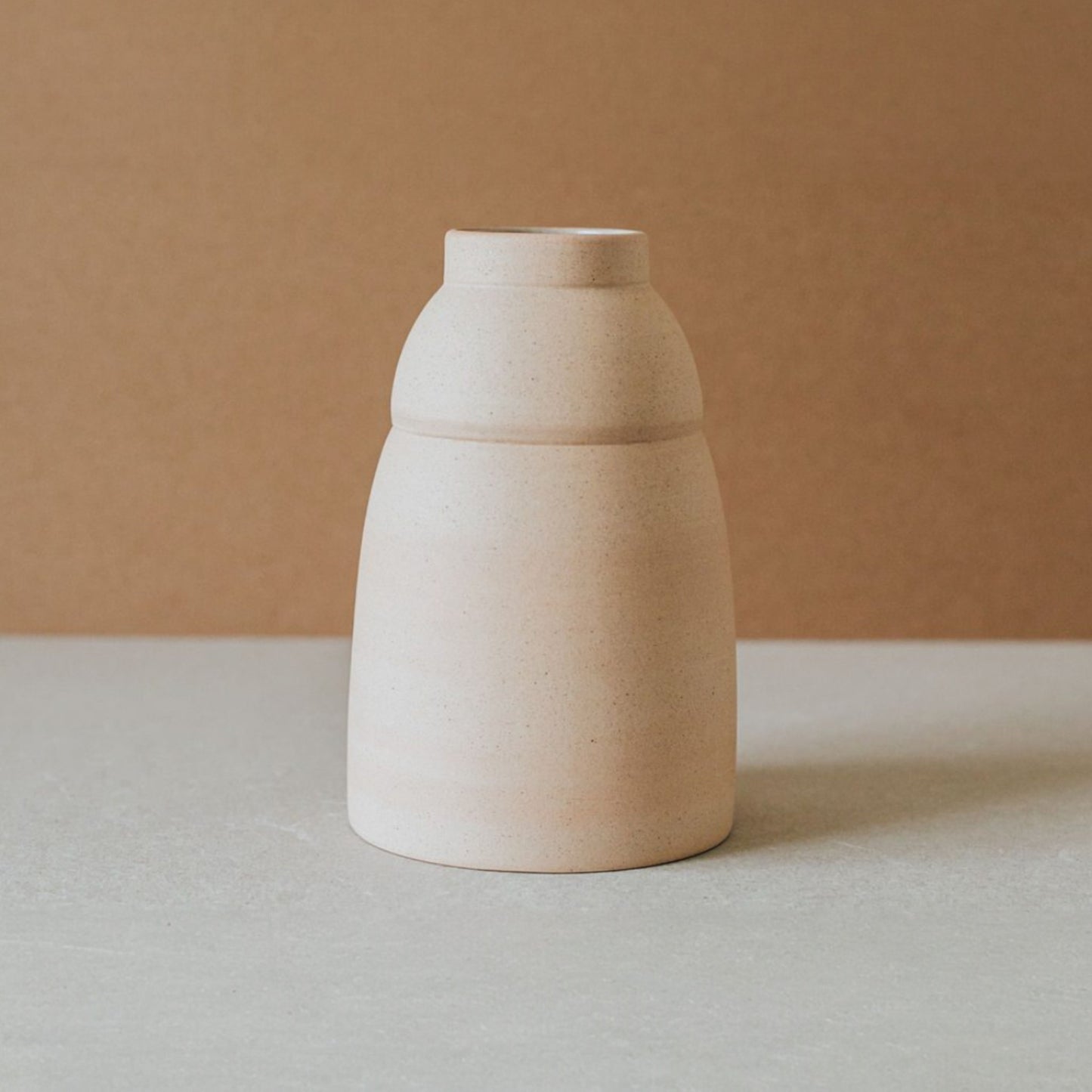Light terracotta rounded ceramic vase with sculptural layered silhouette on neutral background
