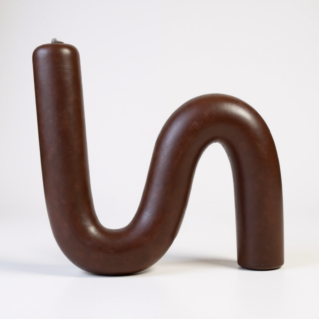 Close-up of a single S-shaped beeswax candle in natural chocolate color