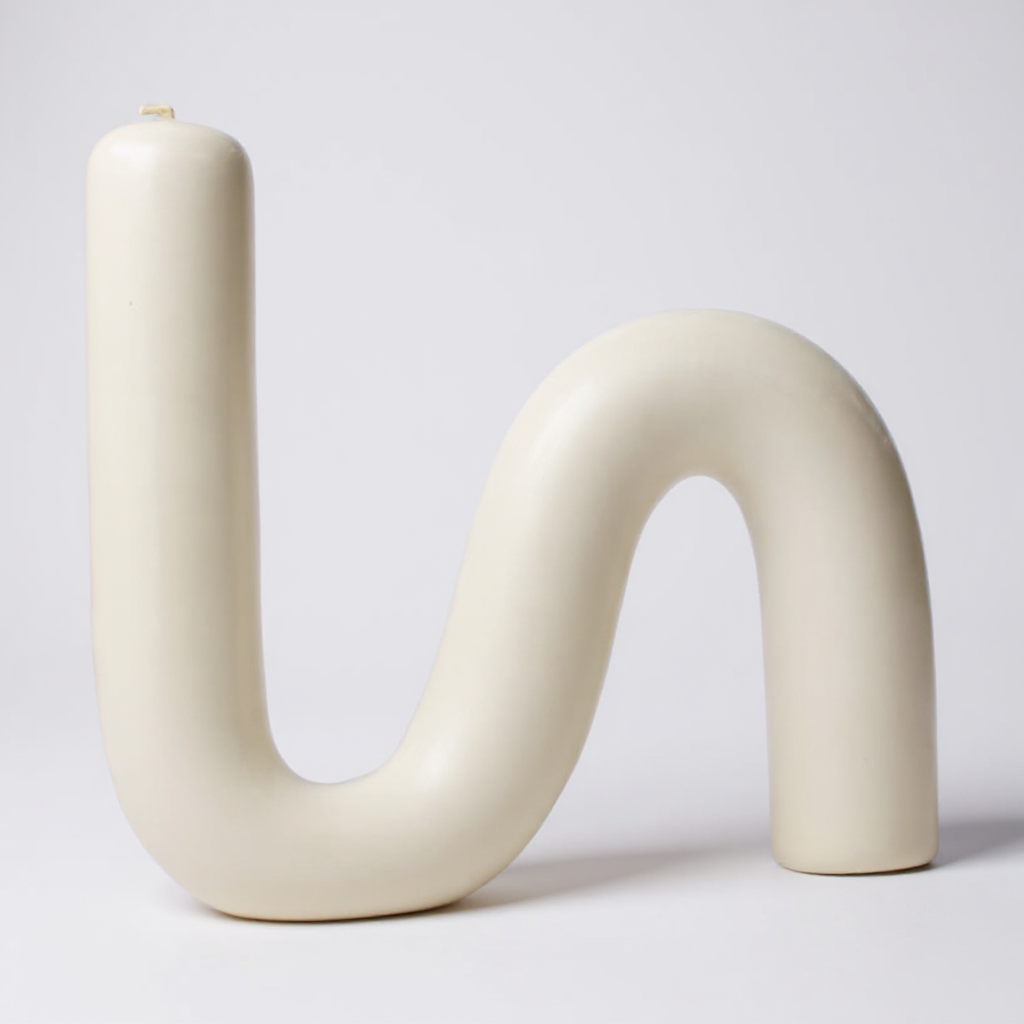 Close-up of a single S-shaped beeswax candle in natural ivory color