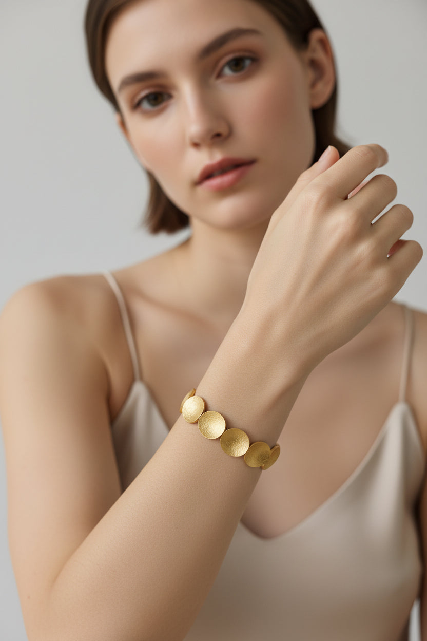 Model posing with silver hammered disc bracelet, clean studio light